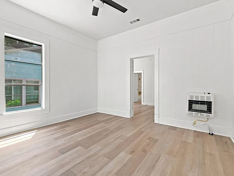 Room featuring light wood-finish flooring, white paneled walls, and a ceiling fan