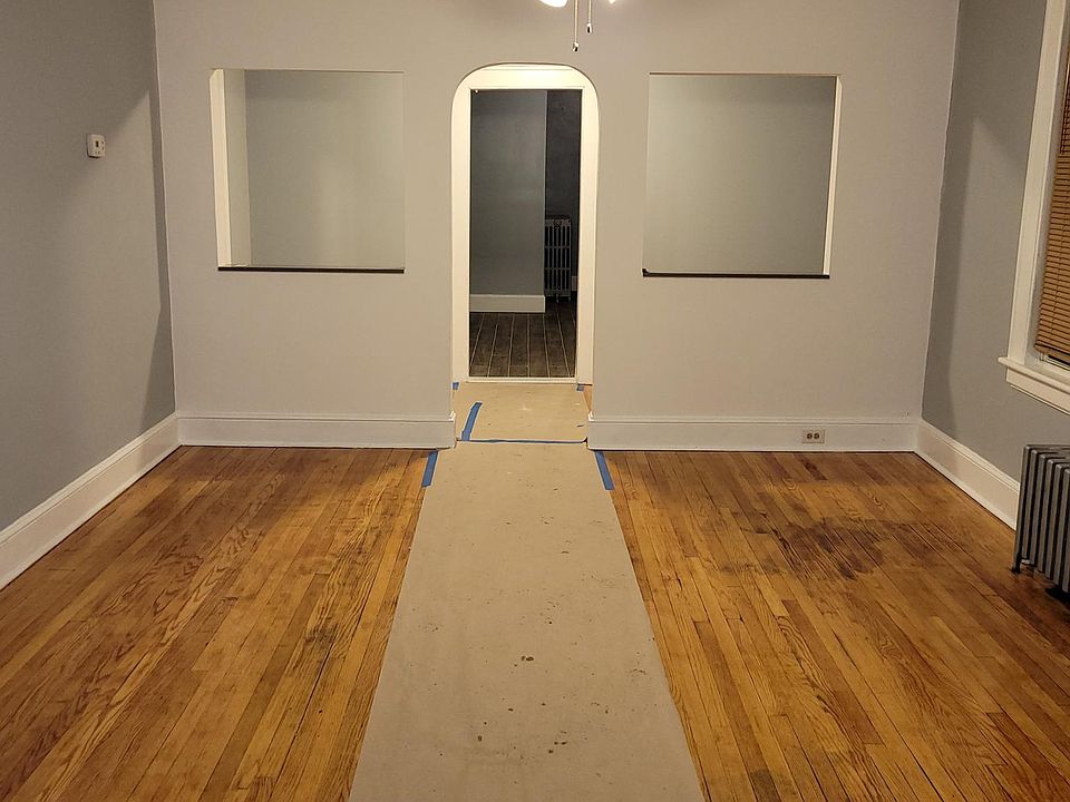 Spacious Living Room with three windows, Hardwood Flooring, wall painted light grey and white