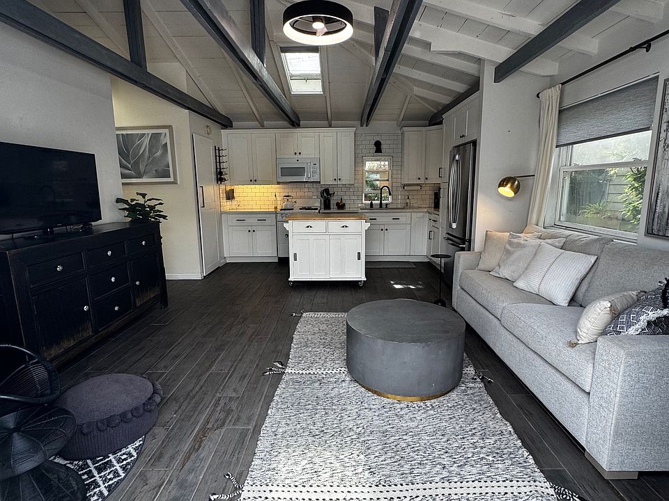 Living room entry (French doors) with vaulted ceiling, open concept, ceiling fan/light and skylight. The space is inviting and perfect for both indoor and outdoor living.