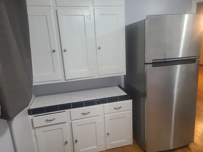 Kitchen with new stainless steel appliances and freshly painted cabinets.