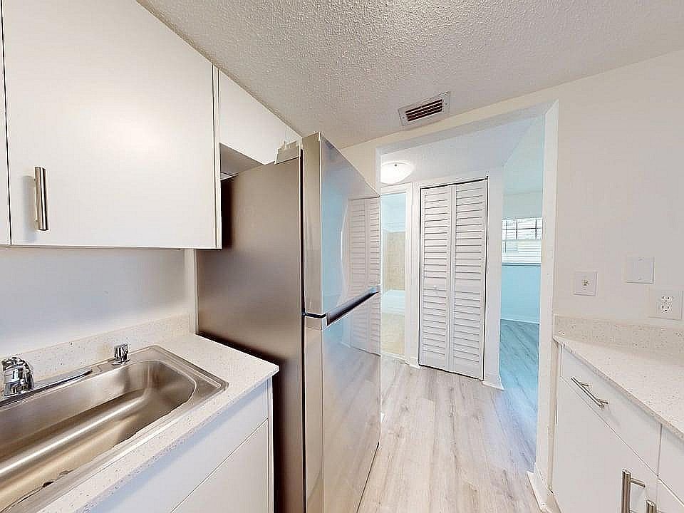 Modern kitchen with sleek stainless steel appliances, bright white cabinetry, and elegant wood flooring creating a fresh and inviting atmosphere.