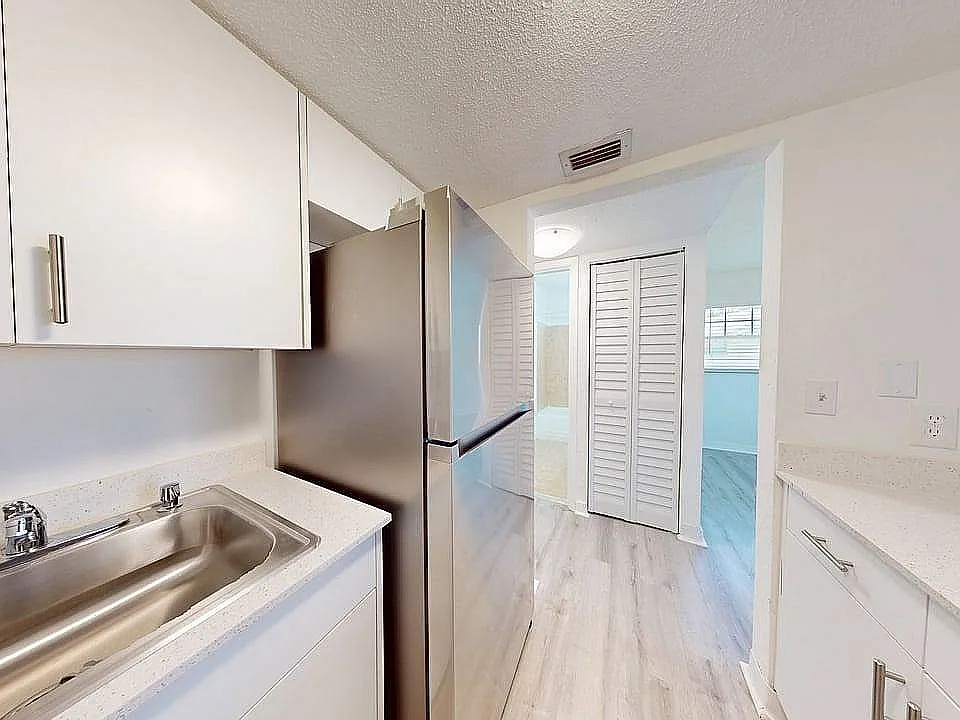 Modern kitchen with sleek stainless steel appliances, bright white cabinetry, and elegant wood flooring creating a fresh and inviting atmosphere.