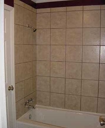 Bath tub with ceramic tiled shower.