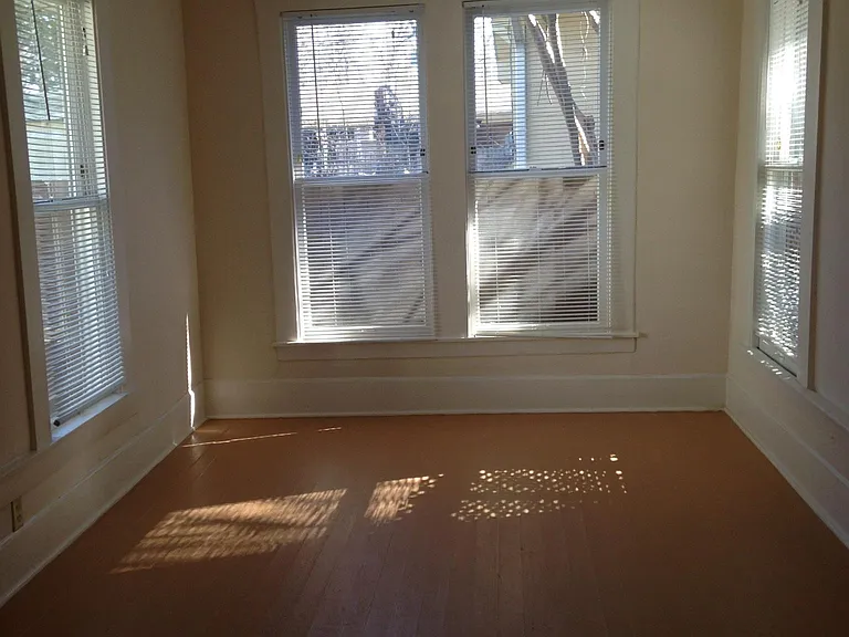 Large back bedroom with many windows and closet space. Hardwood flooring is included throughout the house.