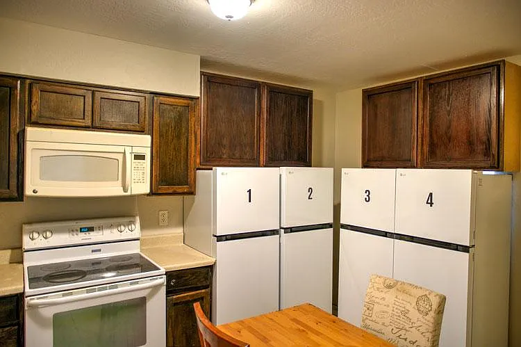 Individual refrigerators for each room with dedicated cabinet above.
