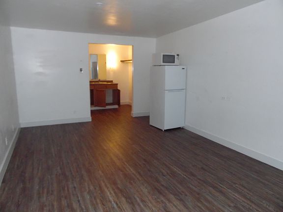 Looking into the large studio apartment, you can see the full size refrigerator and microwave.
