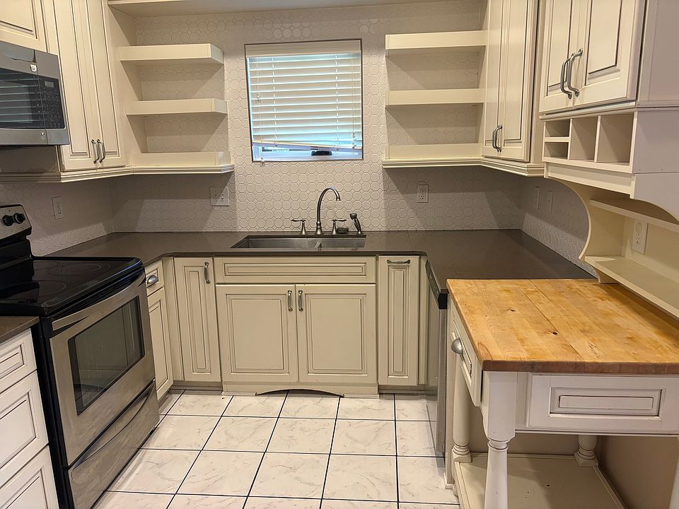 Kitchen with stainless steel appliances, glass top cooktop, and butcher bock