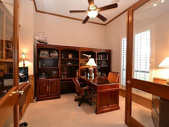 French doors open to the study accented by crown molding, chair rail blocked paneling and built-in bookshelves and desk.