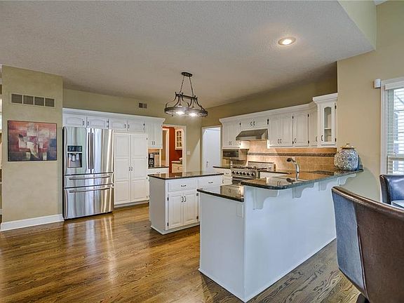 Kitchen features white cabinets, granite counters and stainless steel appliances