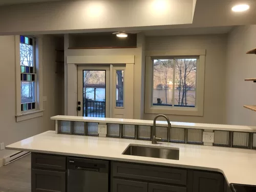 Kitchen with glass block backsplash, quartz countertops, and pleasing view while doing dishes! - 13 Riverview Dr #2