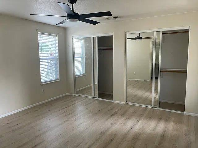 Primary bedroom includes dual closets and ceiling fan as well as door to backyard patio