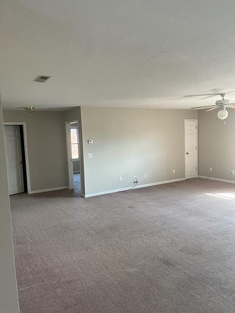 view from kitchen thru living room to bath door on left, bedroom door mid and small utility door on right