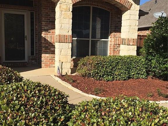 Beautifully landscaped front yard with sprinklers.