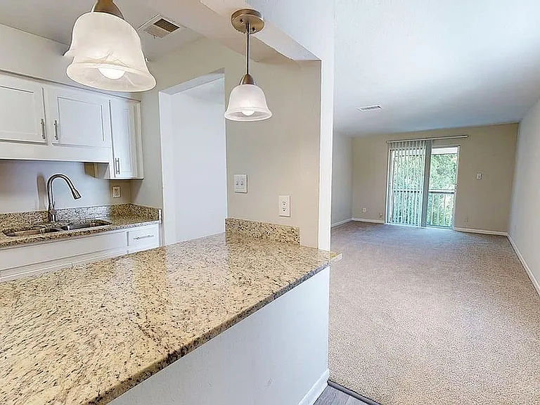 Elegant apartment interior featuring a modern kitchen with granite countertops and an inviting living room with large windows.