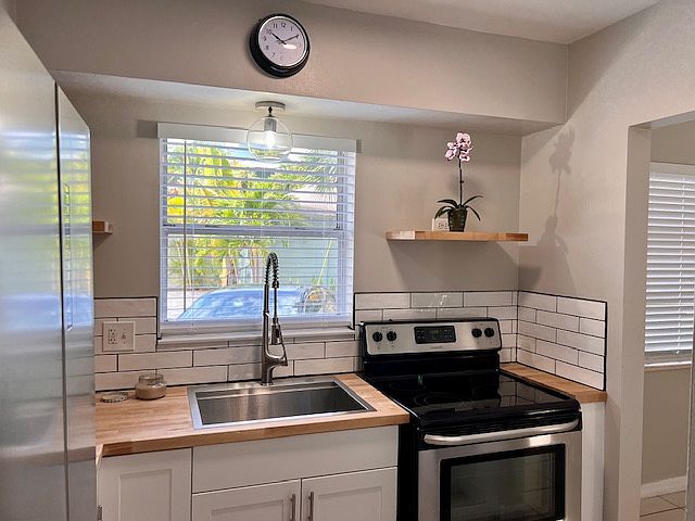 Renovated kitchen with new stainless steel appliances and butcher block countertops.
