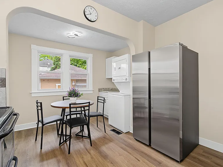 Kitchen nook with a dining set, large window, stainless refrigerator, and convenient in-kitchen laundry closet.