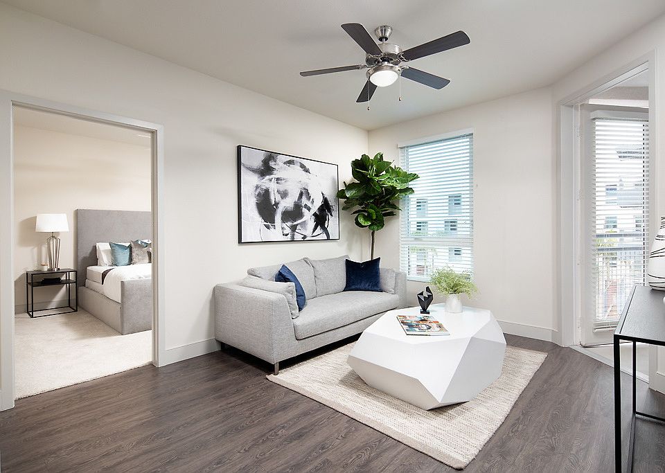 Staged living room with hardwood style, vinyl flooring and ceiling fan. Staged bedroom with carpet.