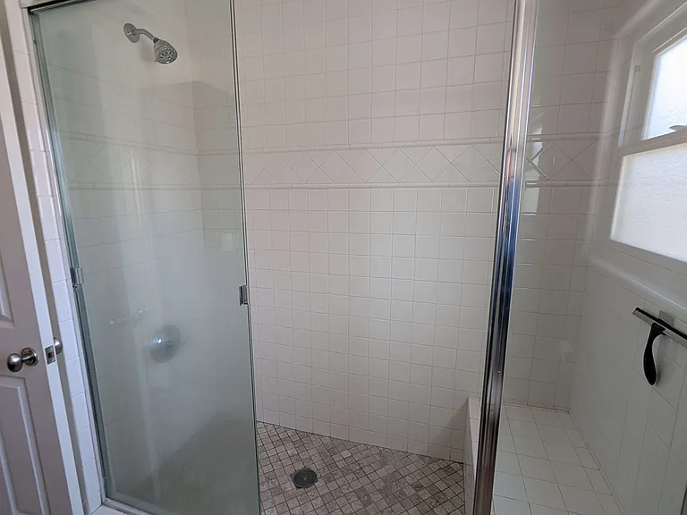 Your bathroom includes a large shower with a bench and sliding glass doors.
