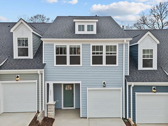 Townhome with blue siding, craftsman style exterior, large widows, garage and two car parking pad in