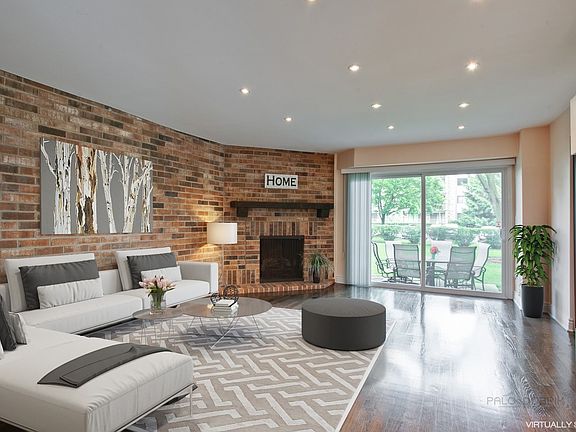 Spacious Living Room with exposed brick wall, walnut hardwood floors and wood burning fireplace.