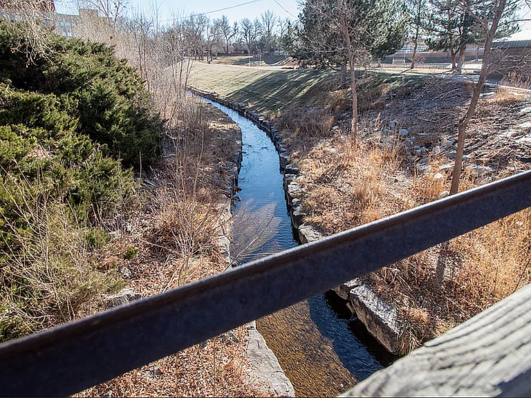 Scenic view of a tranquil stream lined with lush greenery and trees, offering a peaceful natural escape.