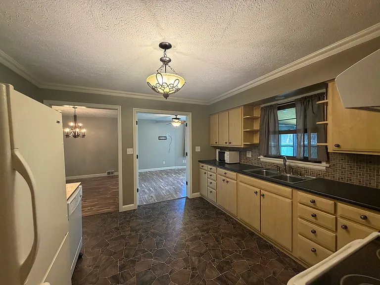 Kitchen connects with dining room, extra room, 1/2 bath and large laundry room with storage.