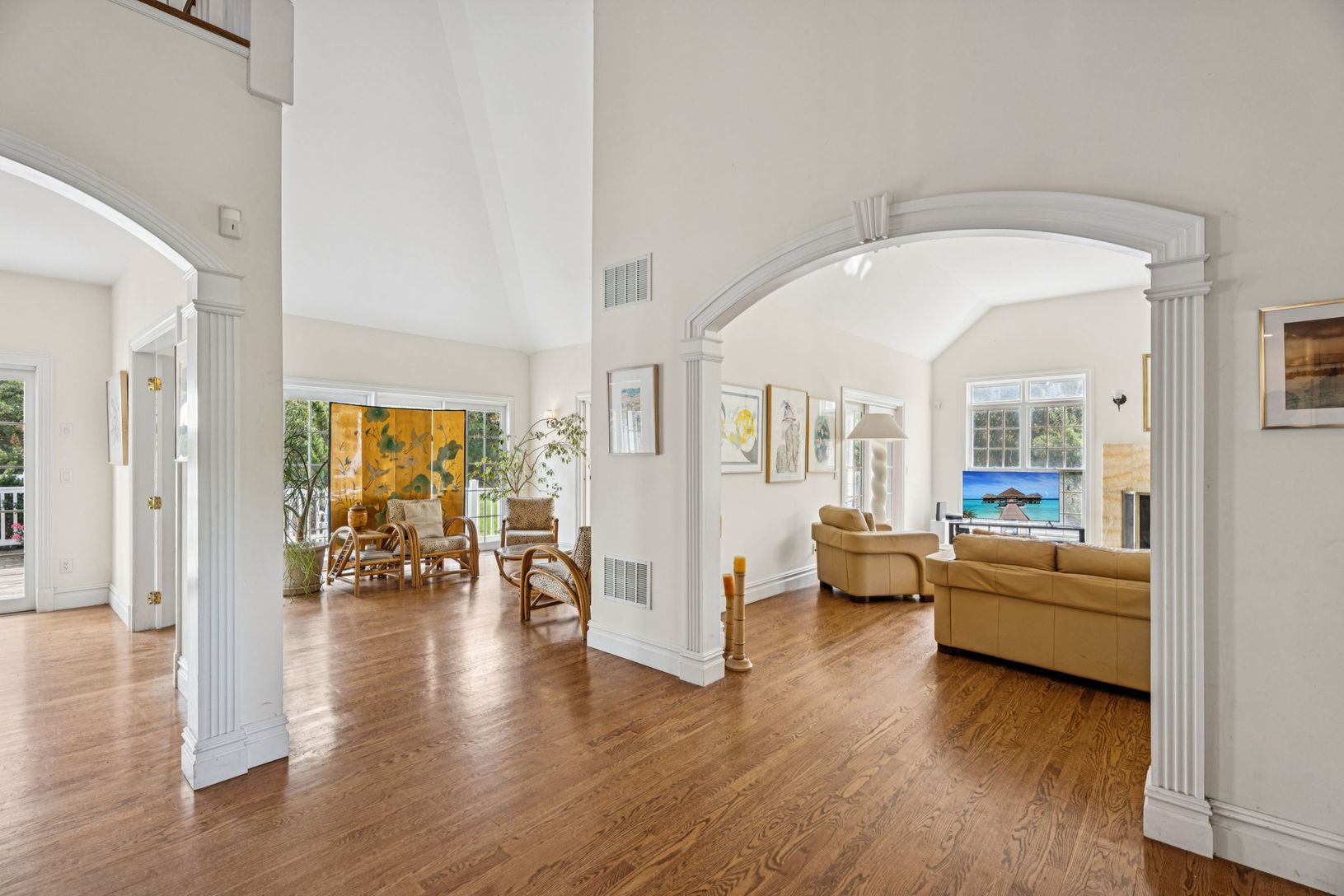 An impressive foyer adorned with oak flooring, vaulted cathedral ceilings, and arched walkways