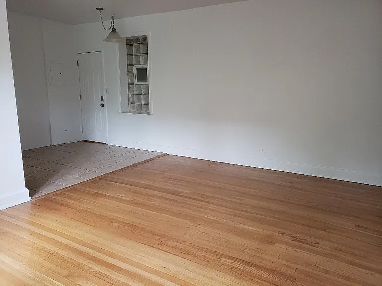 Living room view w windows behind you to show LOTS OF SPACE, NEW PAINT, and GLEAMING HARDWOOD FLOORS, plus glass brick window for extra light and ventilation to create a breeze in the kitchen