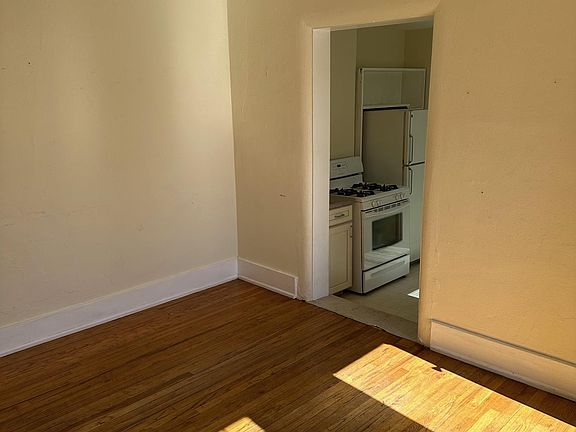 Living room with great natural light & wood floors, looking toward kitchen.