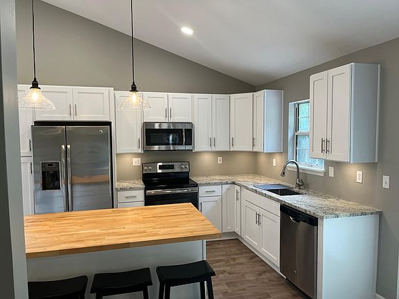kitchen with new flooring, granite and butcher block countertops fixtures and cabinets