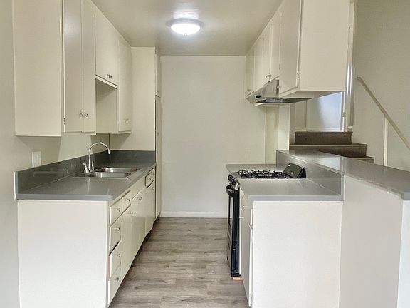 Galley kitchen with gas range, double sink, plenty of cabinet space, quartz countertops, and breakfast bar