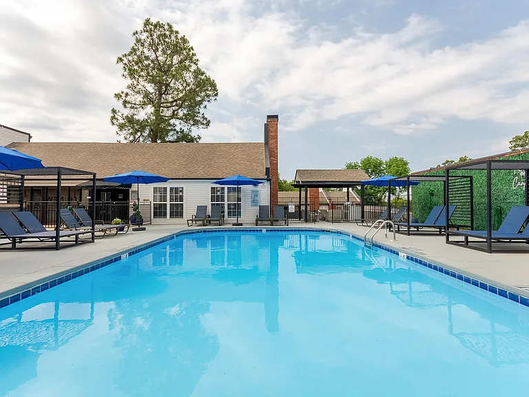 A sparkling swimmin gpool with sundeck and tandem chaise lounge chairs is shown at ReNew on Cantrell.