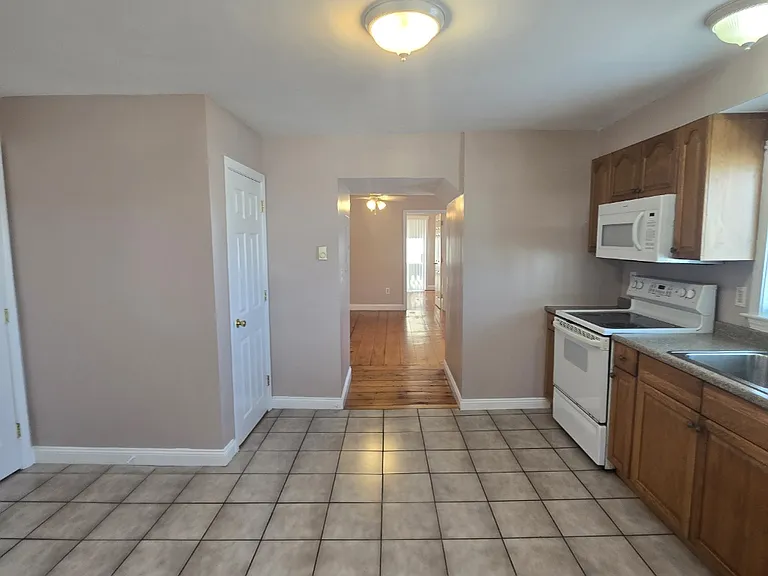 Kitchen with tiled floors looking into living room