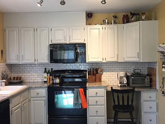 Renovated kitchen with granite countertops, a butcher block island and subway tile backsplash