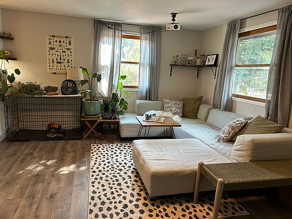 The large living room has two wide double-hung, screened windows and is adjacent to the entryway door.