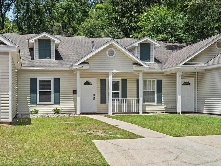 Siding exterior featuring a partial front porch with white railing, dormer windows with dark shutters, and an arched transom entry door