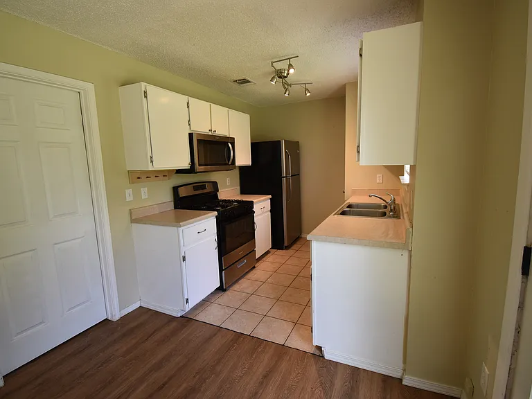 Kitchen features staining steel appliances. The door on the left leads to a laundry room and then the garage