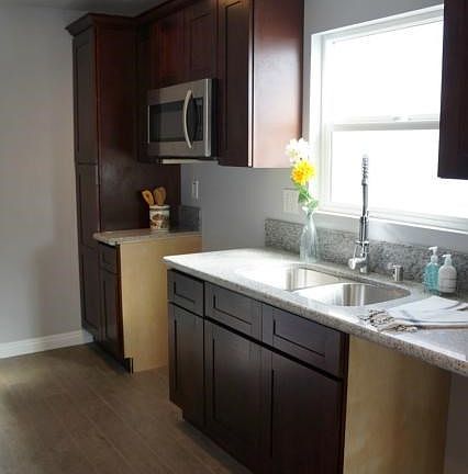 Bright and airy kitchen with dark cabinets and light granite. New kitchen window lets in natural light. Range and dishwasher to be installed shortly. Also built in microwave over the stove area.
