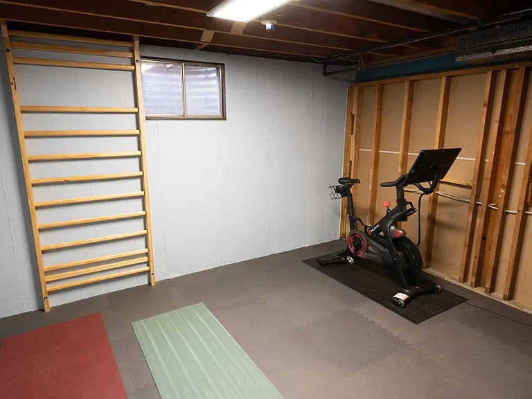 Exercise room with a Swedish ladder, foam flooring, and a north-facing window.