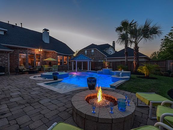 Resort style back yard features firepit and a gorgeous pool, spa and in ground covered bar area.
