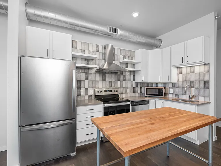 Modern kitchen with stainless steel appliances, stylish gray tile backsplash, and sleek wooden island creating a contemporary space. Modern kitchen with stainless steel appliances, stylish gray tile backsplash, and sleek wooden island creating a contempor