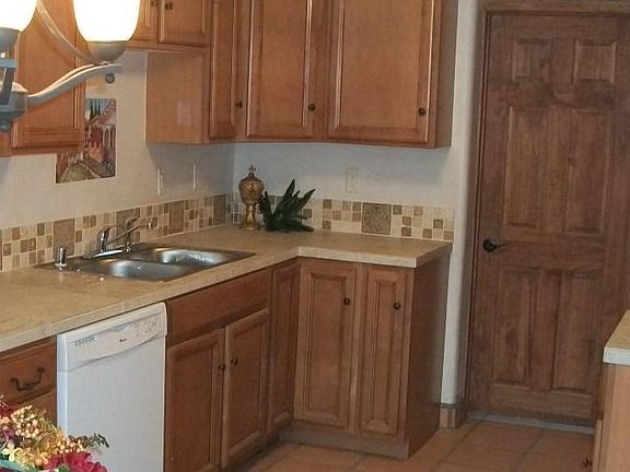 Kitchen has Dishwasher, stainless steel double sink. Has Gas Stove/Range. Micro-wave & Fridge. All appliances are White. Cabinets are a cinnamon color with one lazy Susie in the corner.