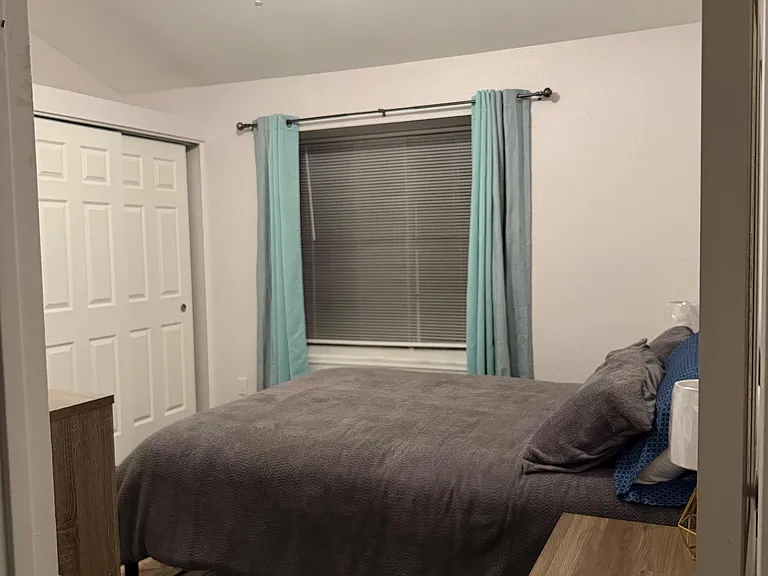 Furnished bedroom with a ceiling fan, window with curtains, and a closet for convenient storage.