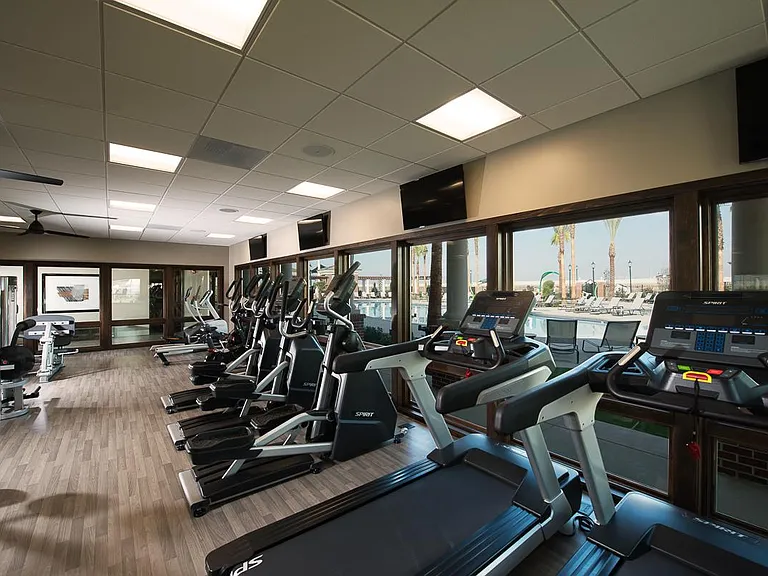 The gym room with windows looking to swimming pool area