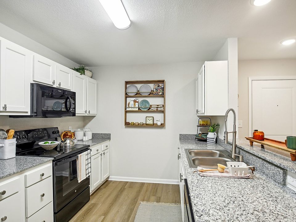 Upgrade your lifestyle with a modern kitchen featuring granite countertops and sleek black appliances at The Preserve Murfreesboro.