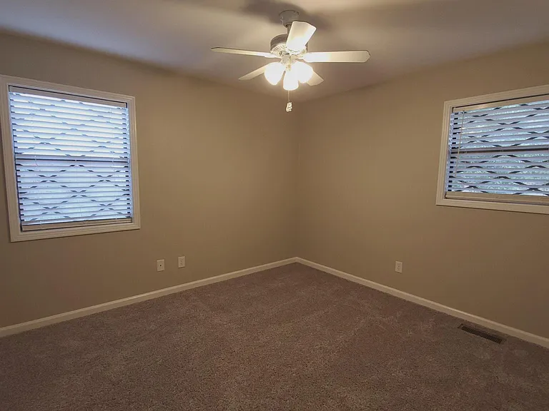 Secondary bedroom with new carpet, ceiling fan, large closet, window blinds, and neutral colors.