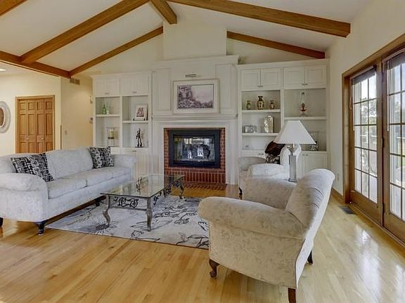 Living room with gas fireplace, custom built-in shelves and a door leading to the deck.    A large wall of windows in this room shows the wonderful views of the golf course