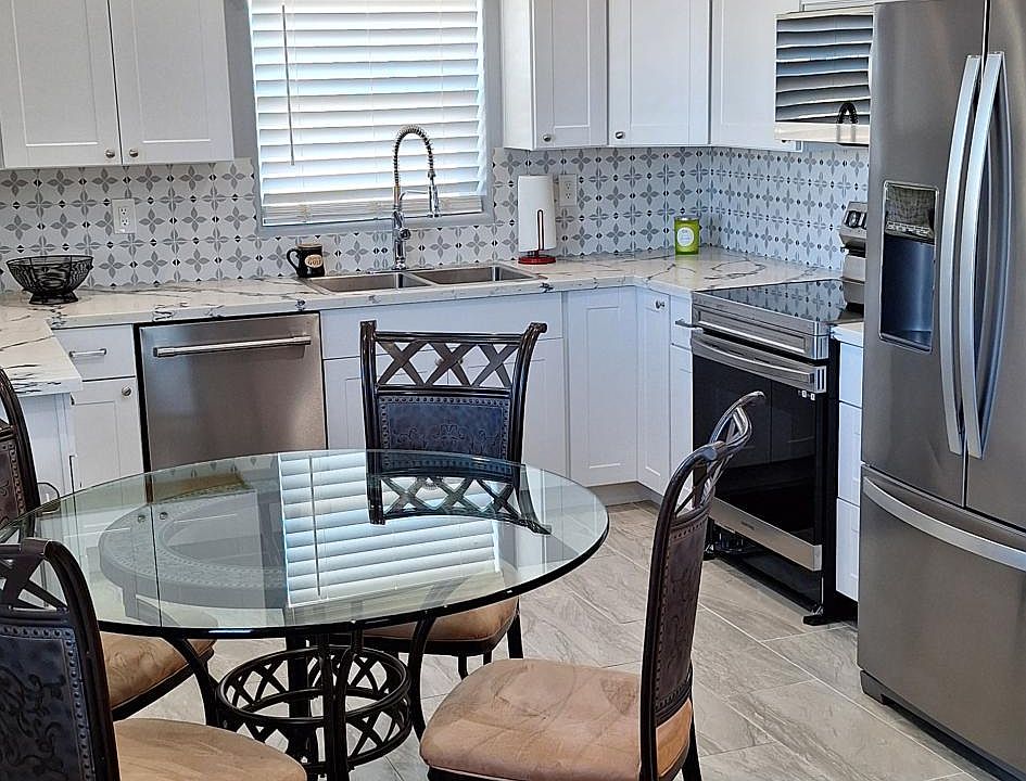 Kitchen with refrigerator, dishwasher, microwave, electric stove, coffee maker, table and 4 chairs.
