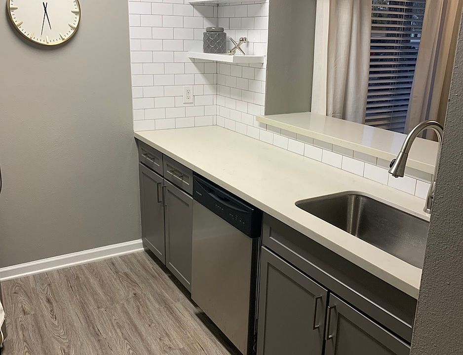 Interior kitchen Room with dishwashing view with A Wall Clock at Trailwood Village Apartments in Kingwood, Texas.