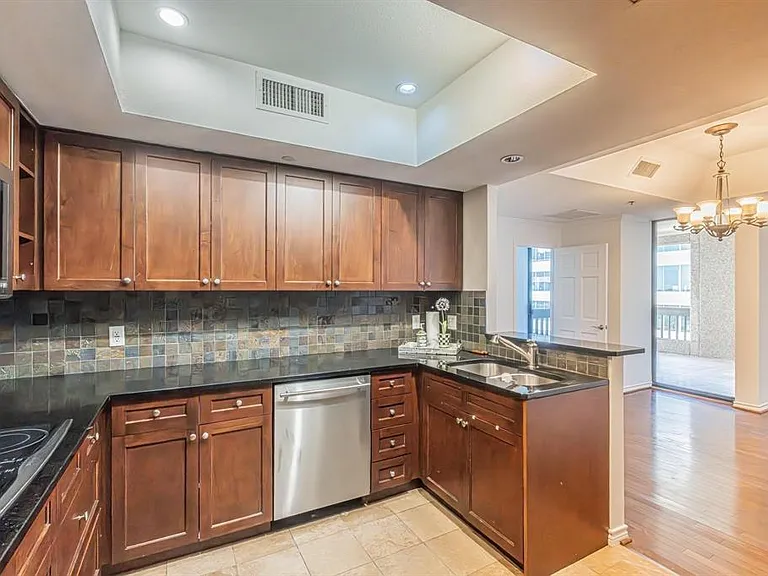 Kitchen featuring wood cabinetry, dark countertops, a tile backsplash, and stainless steel appliances